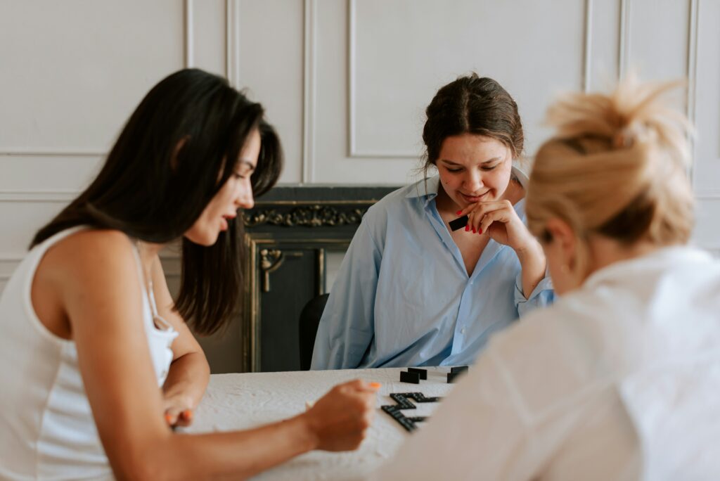 a group of three women playing a game and being a good friend to one another