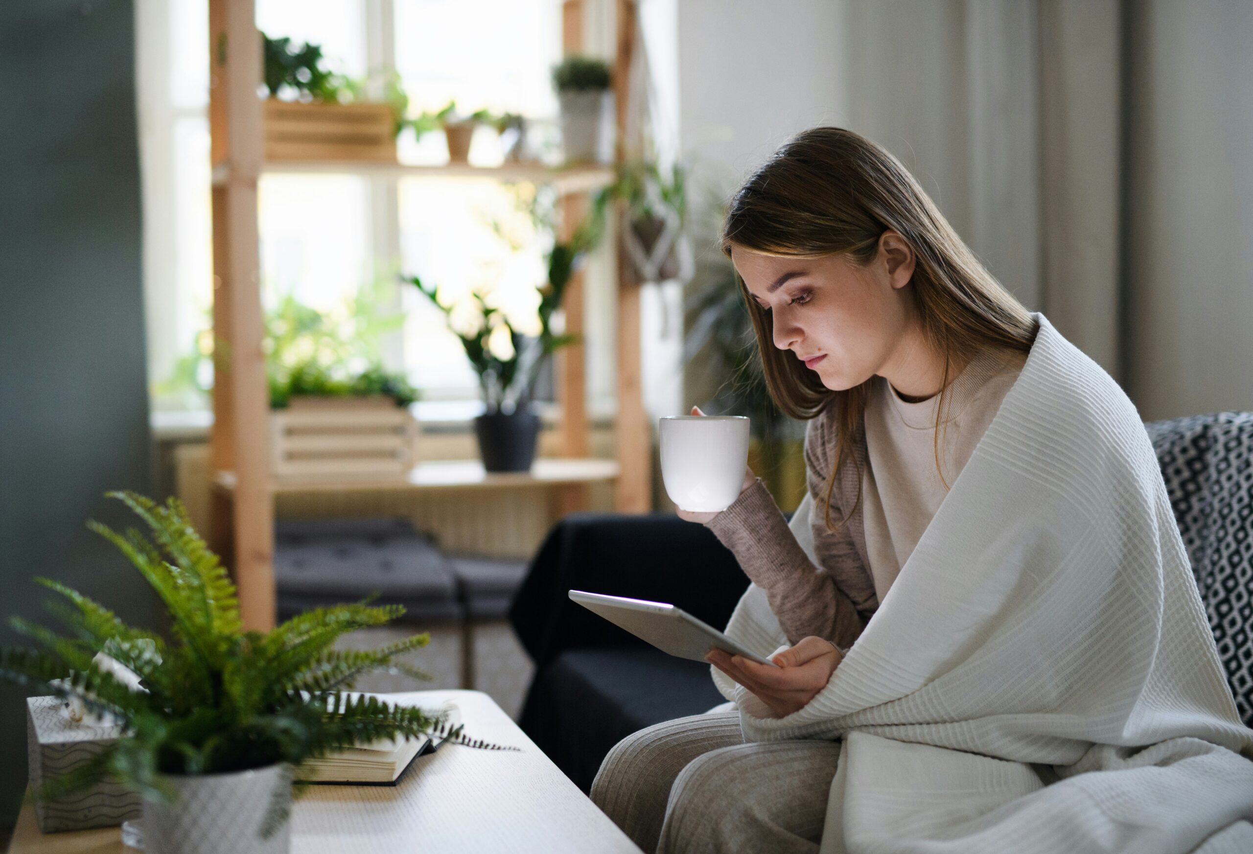 woman experiencing burnout disconnecting with coffee and scrolling on a tablet